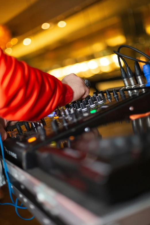 a dj working on an electronic device with other equipment nearby