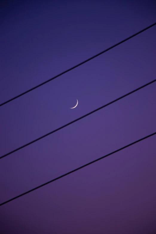 a crescent moon and its shadow against a purple sky