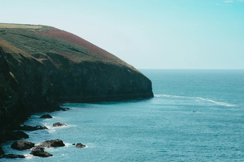 a rock covered shoreline near a hill side