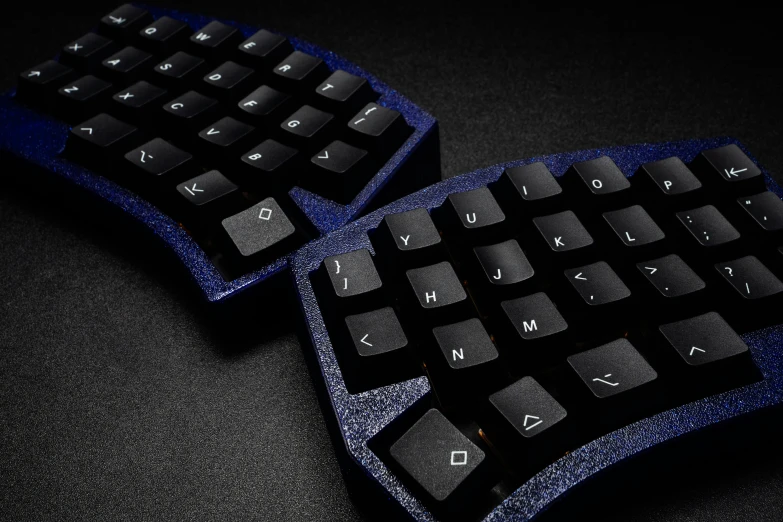 two black and blue computer keyboards sit together on a table