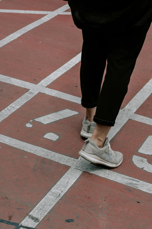 a person with sneakers on walking across a parking lot