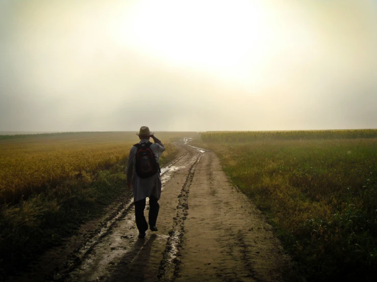 a woman with a backpack walking down a dirt road
