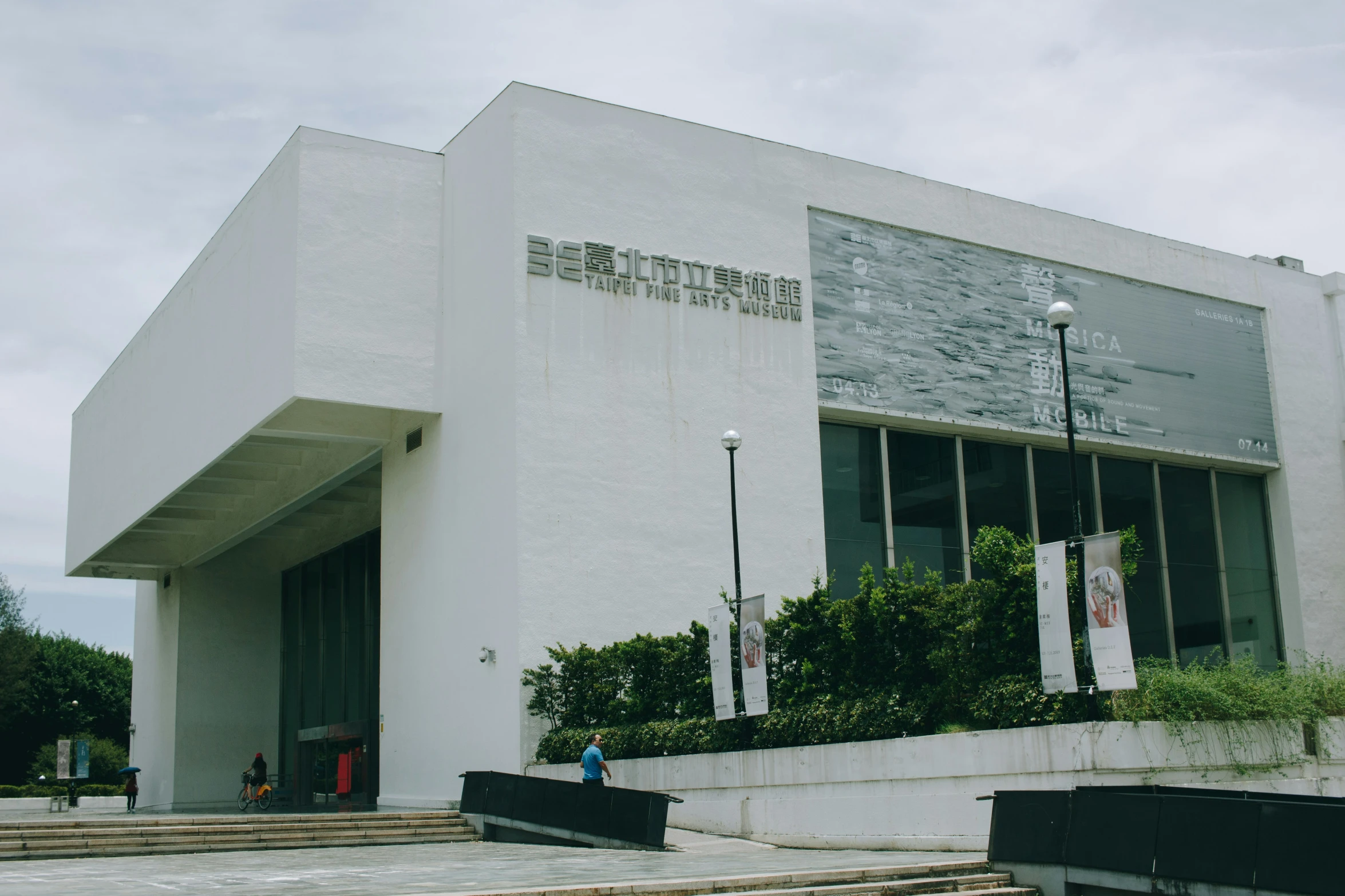 people are walking on the sidewalk near the museum