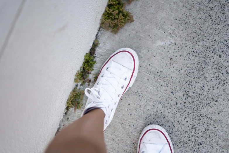 an overhead s of someones feet in white converse sneakers