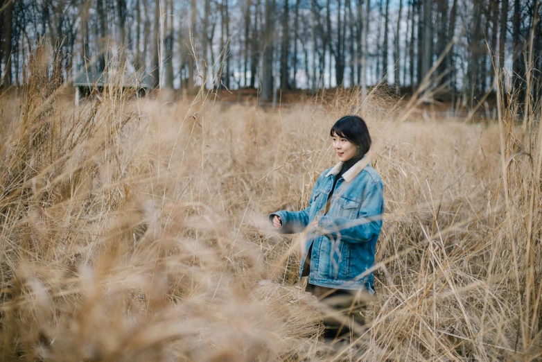 young person sitting in long brown grass alone