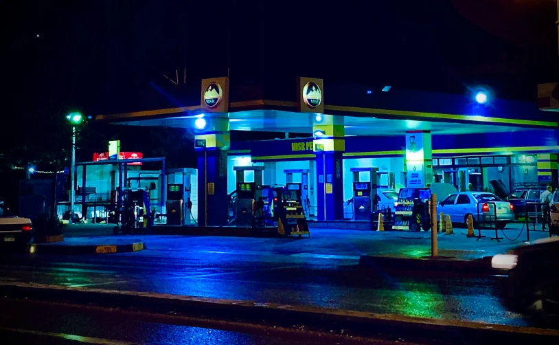 a brightly lit gas station with lots of cars parked