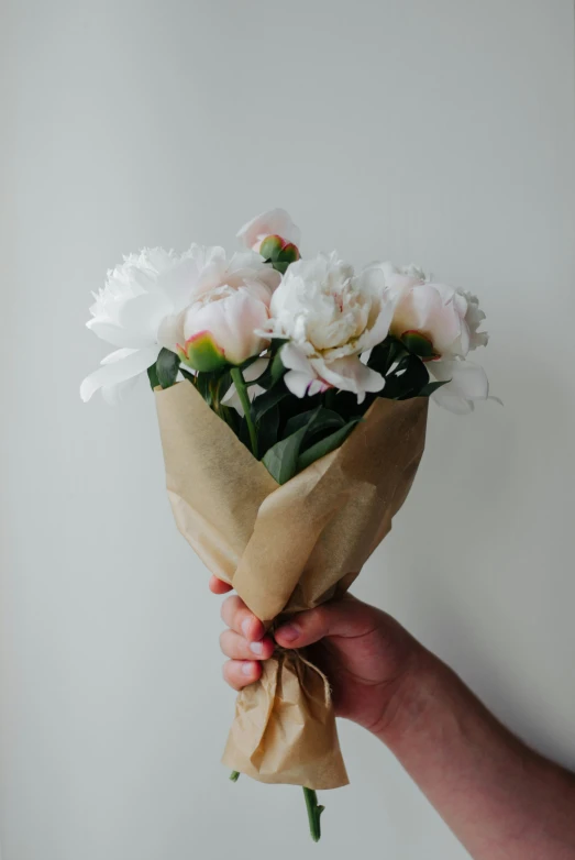 a person holding a bouquet of white and pink flowers