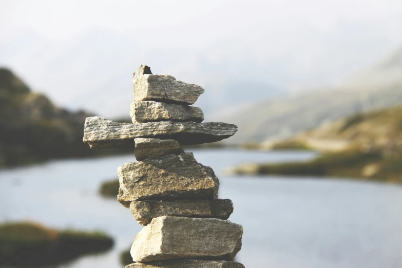 stacked rocks near a lake with mountains in the background