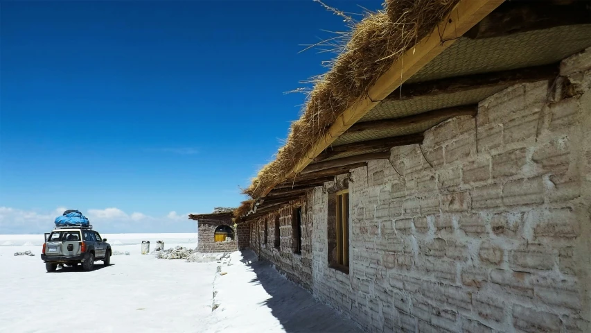 a pickup truck parked in front of a thatched house