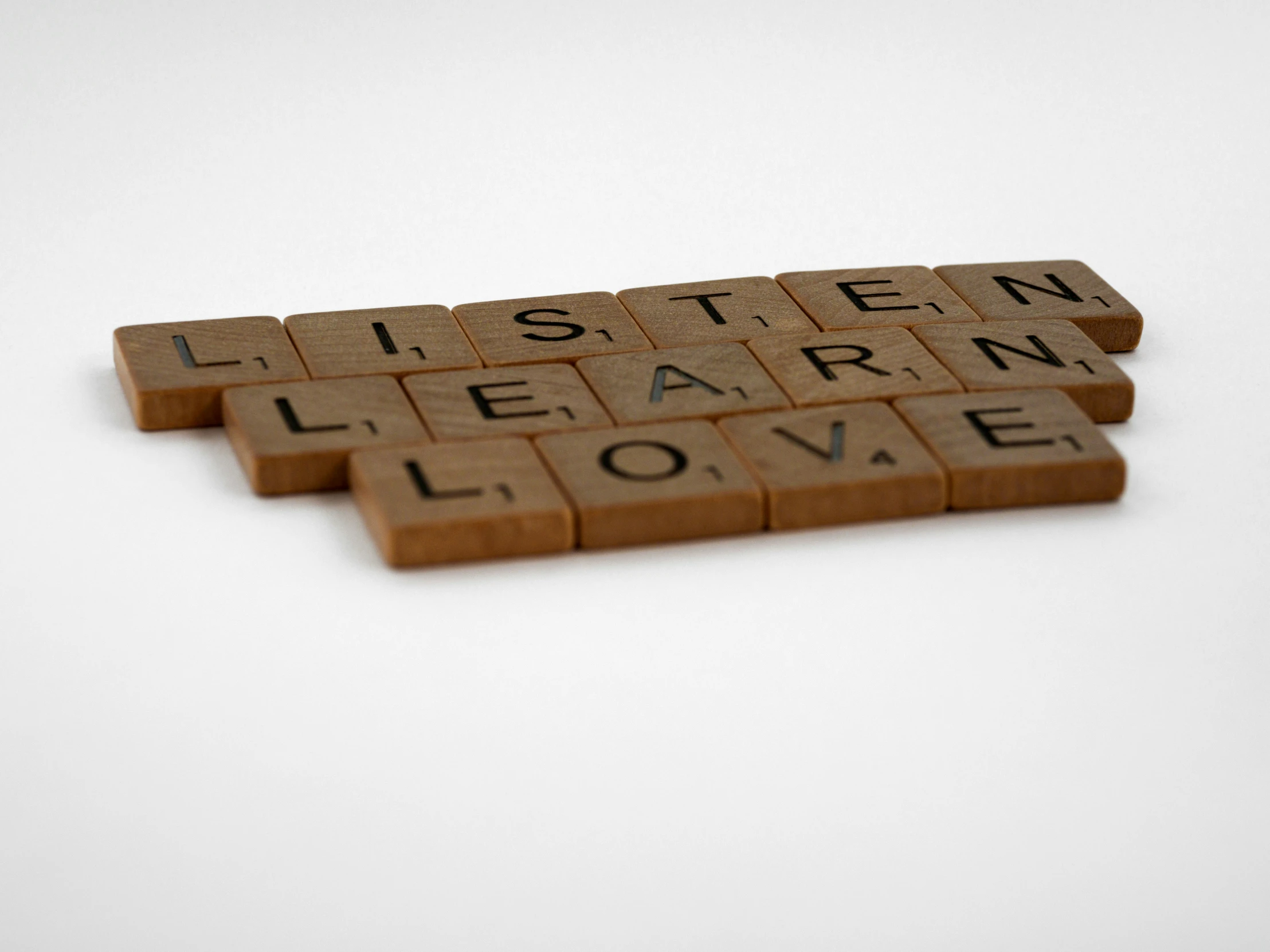 three small tiles with the words listen learn love spelled on it