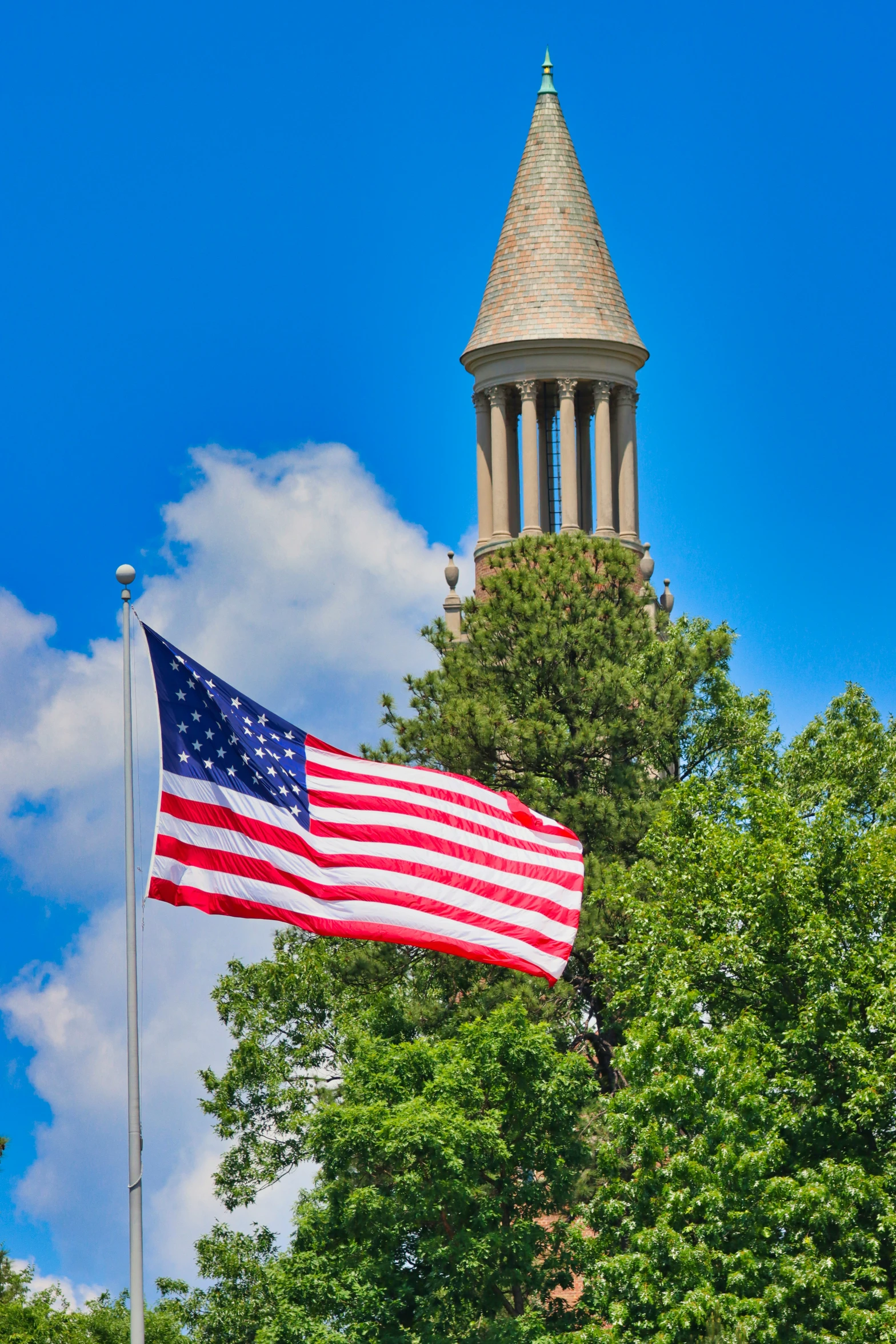 the flag is waving next to a clock tower