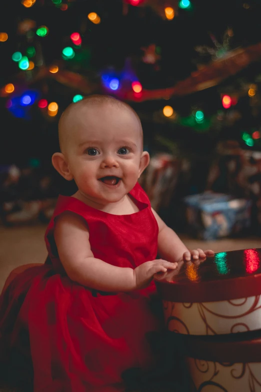 baby in a red dress with christmas ornaments