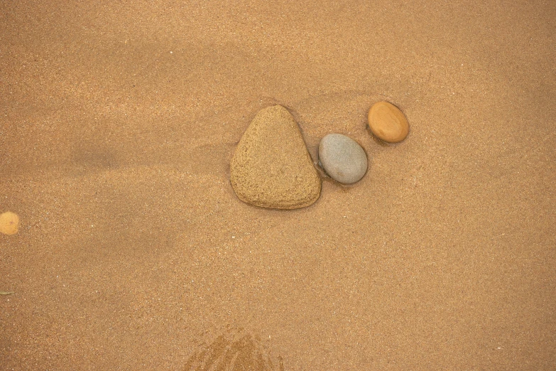 three stones in the sand with one rock on top