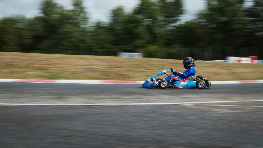 a person on a blue racing kart with two people in it