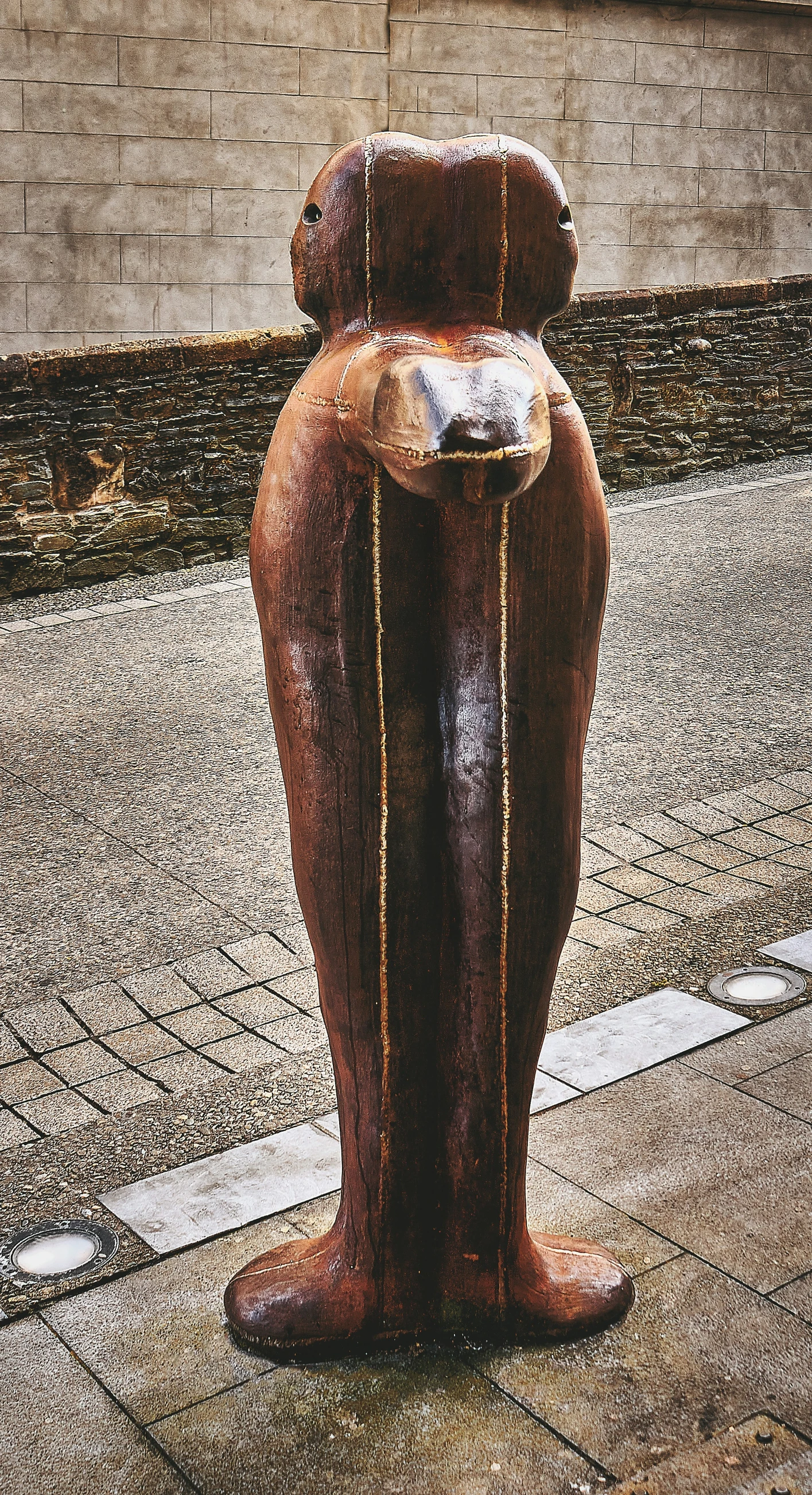 a statue of a seated person is on the sidewalk