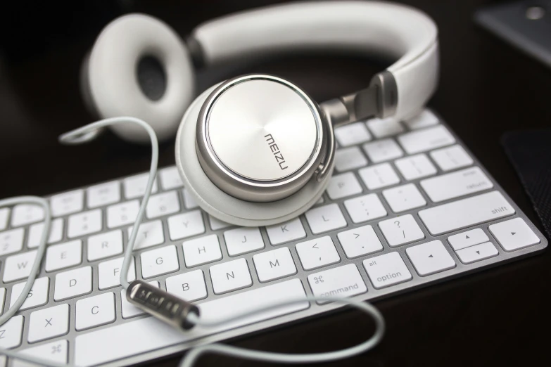 a white stereo headphones sits on a keyboard