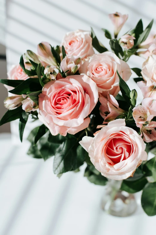 a glass vase filled with pink roses on top of a table