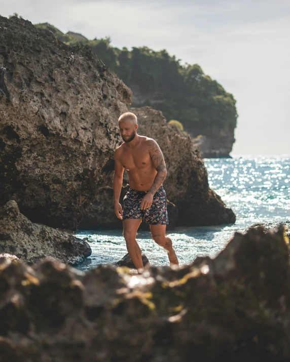 a man is wading in the water next to a large rock