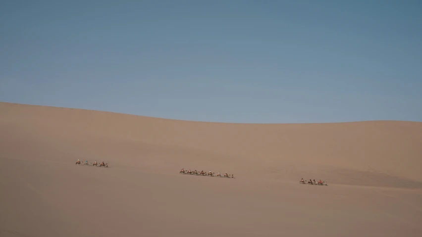 a group of people ride on a dune