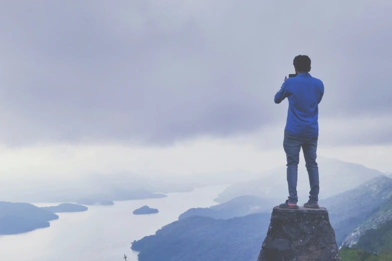 a person standing on top of a mountain taking pictures