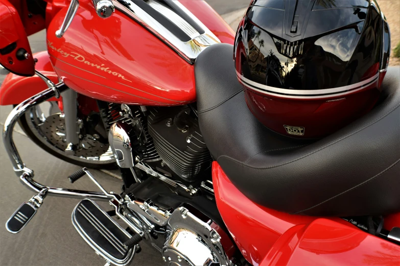 a red motorcycle parked on a street with a black helmet on the side