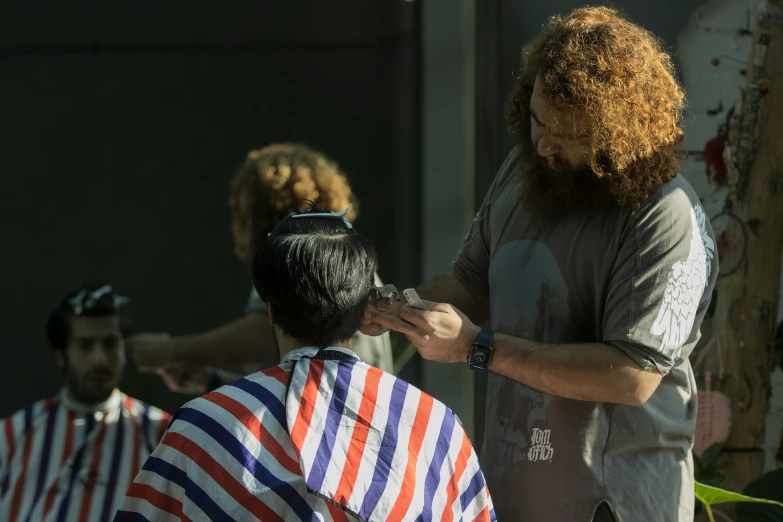 the man has long red and white hair, while the other person in black and orange striped shirt is at his side