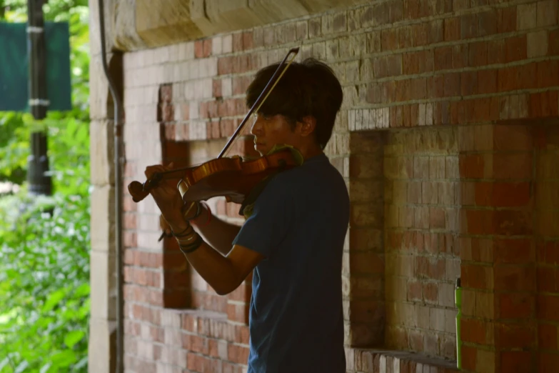 a young man playing violin next to a building