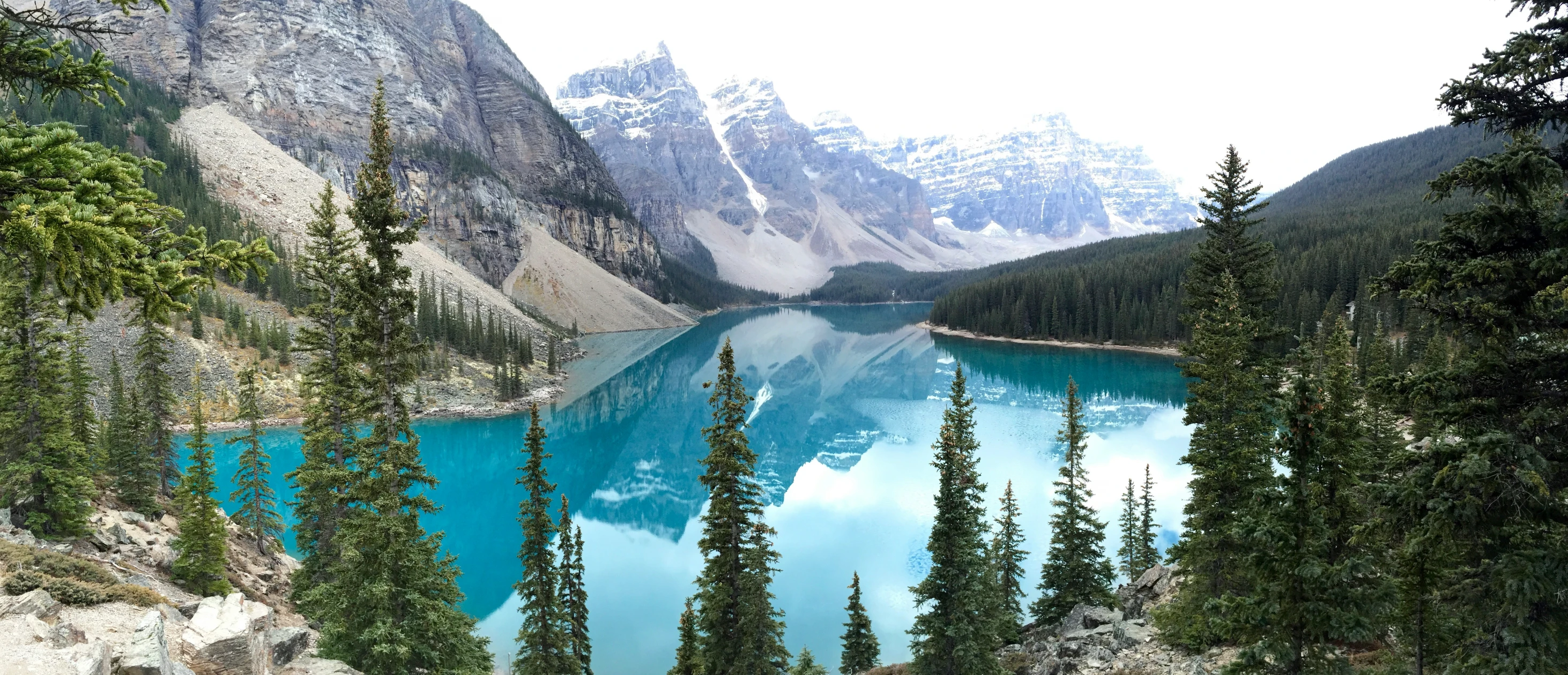 blue water sits between green trees near mountains