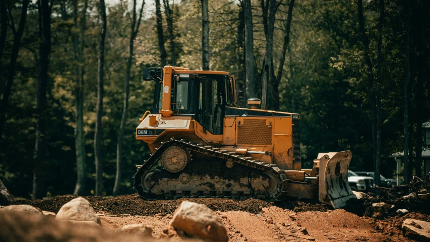 an orange bulldozer on dirt near trees