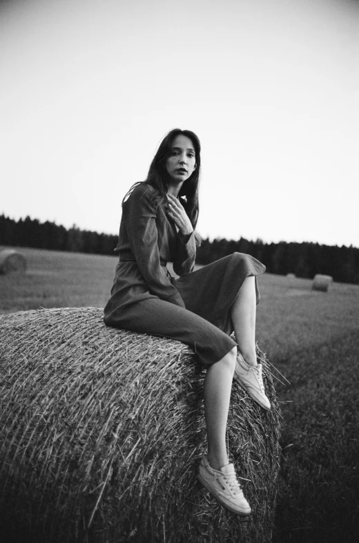 a woman sitting on top of a hay bale