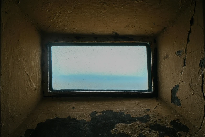 an empty window in a dirty and peeling building