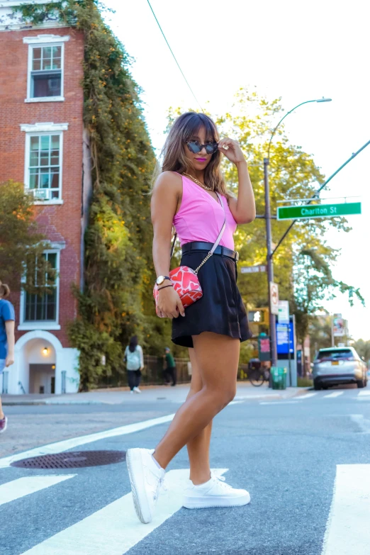 a woman with dark hair and sunglasses standing in the street