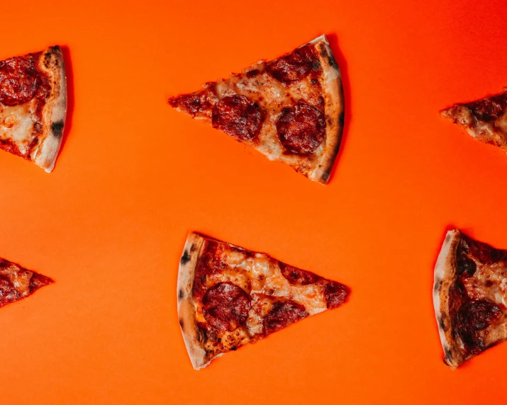 four slices of pizza sitting on top of an orange surface