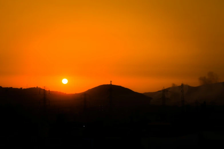 a sunset with a plane and mountains in the background