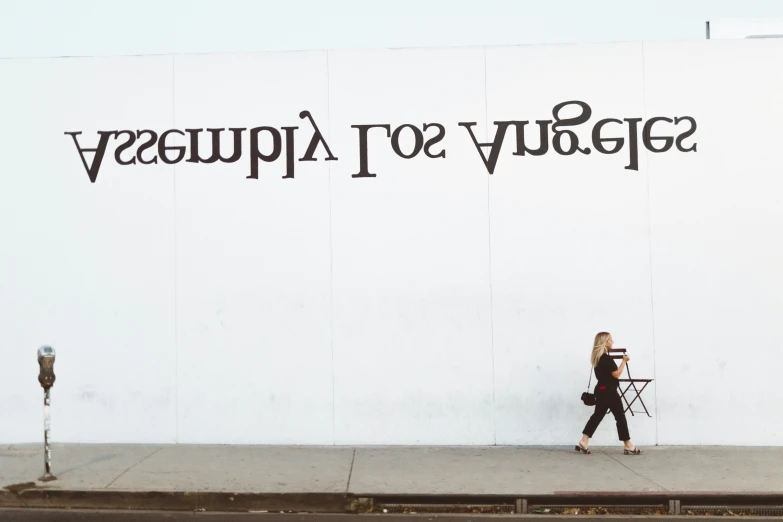 woman walking past building wall advertising her new fashion line