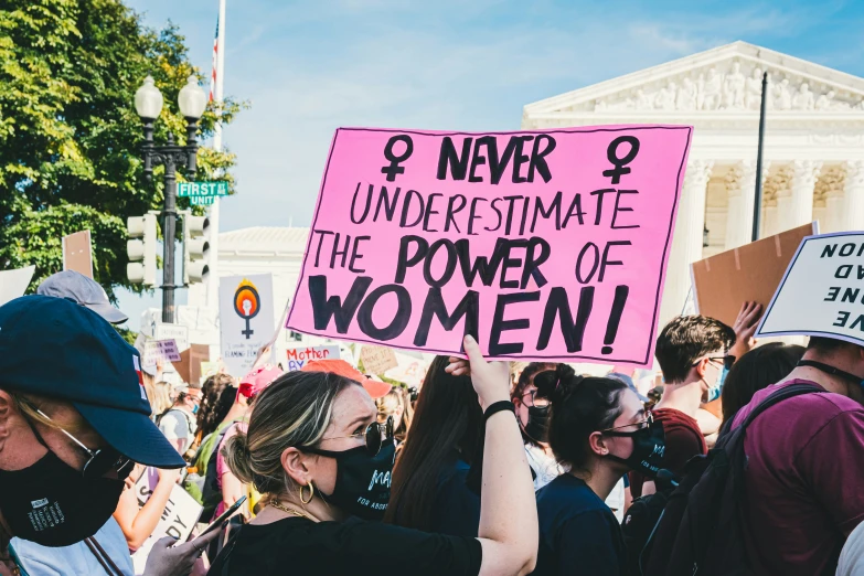 a protest in front of the white house with a sign saying never underestimate the power of women