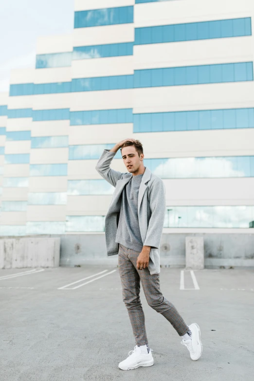a man standing in front of a tall building wearing sweatpants and sneakers