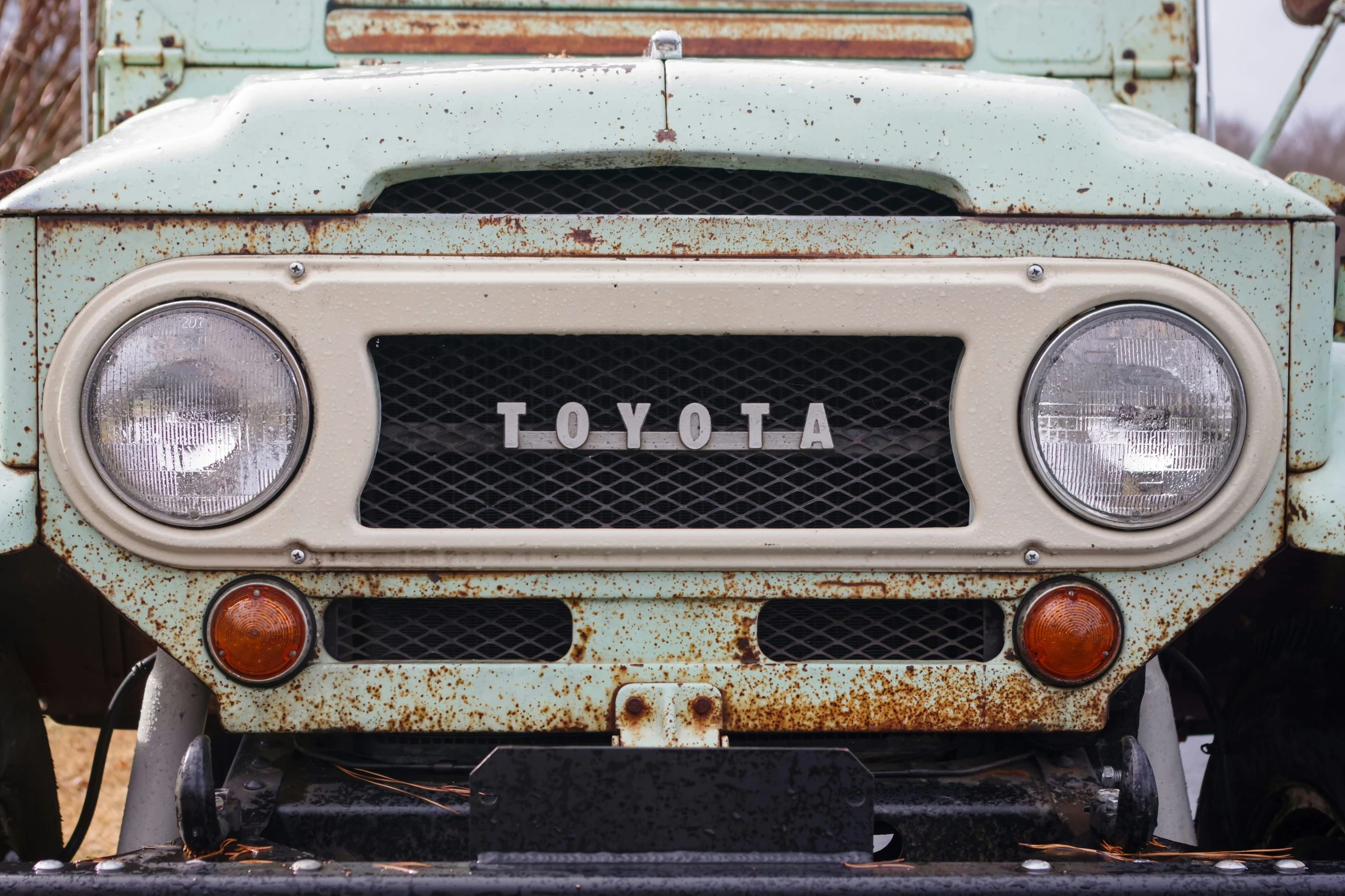 an old rusted truck is shown with a toyota light on it