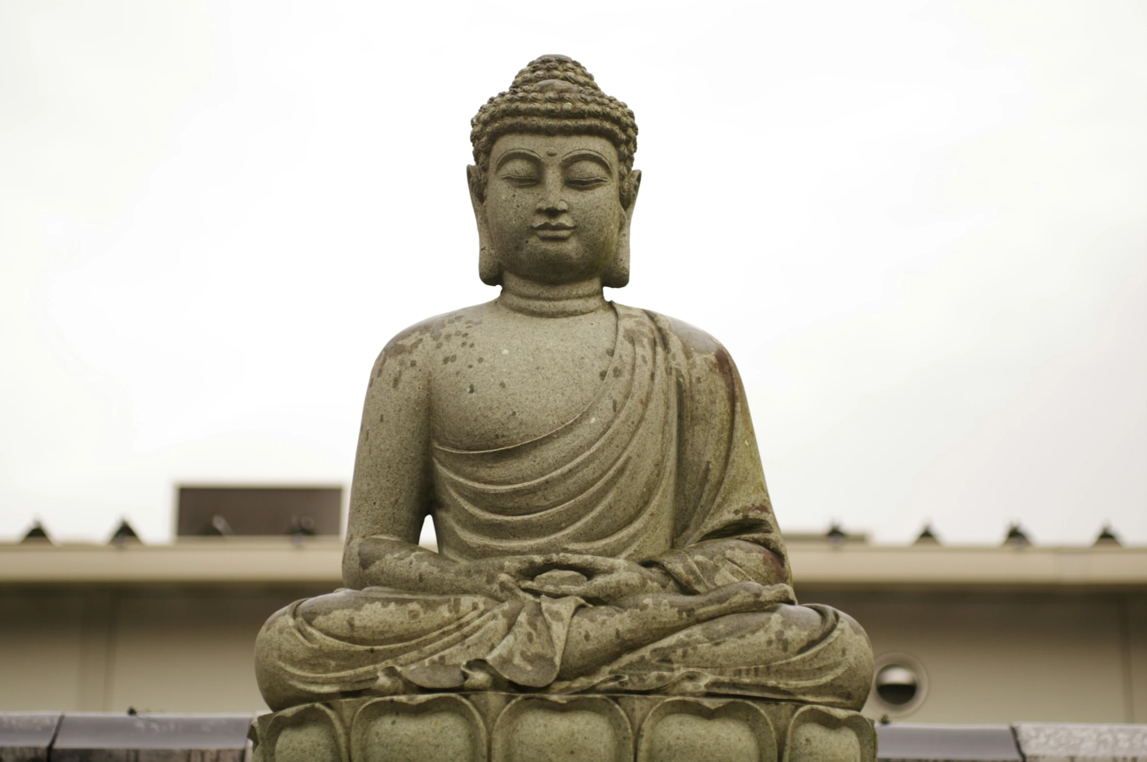 a stone buddha statue sitting in front of a building