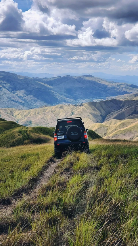 an suv drives down a grassy hill on a sunny day