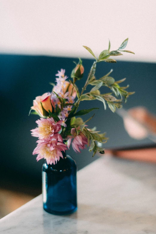 a blue vase has flowers in it sitting on the table