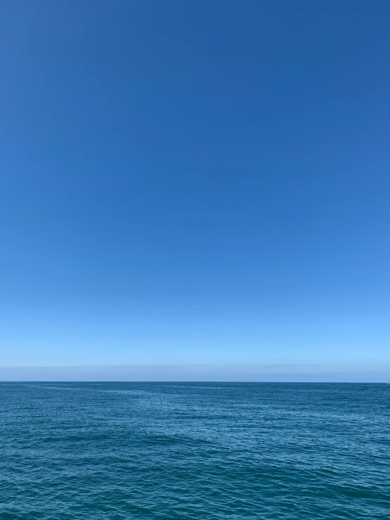 two people stand in the ocean with an airplane flying above them