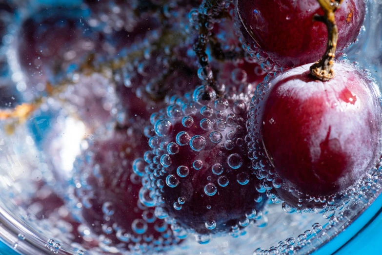 cherries in water sitting on top of a glass