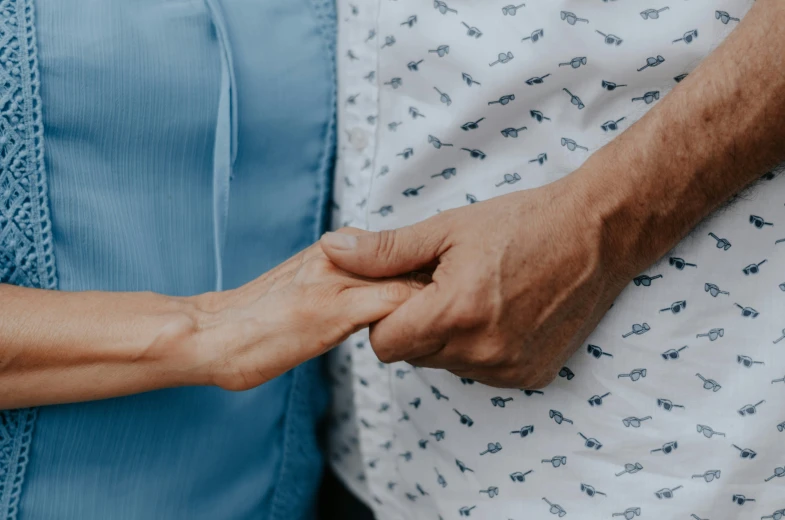 a man and woman hold hands while standing in a blue dress