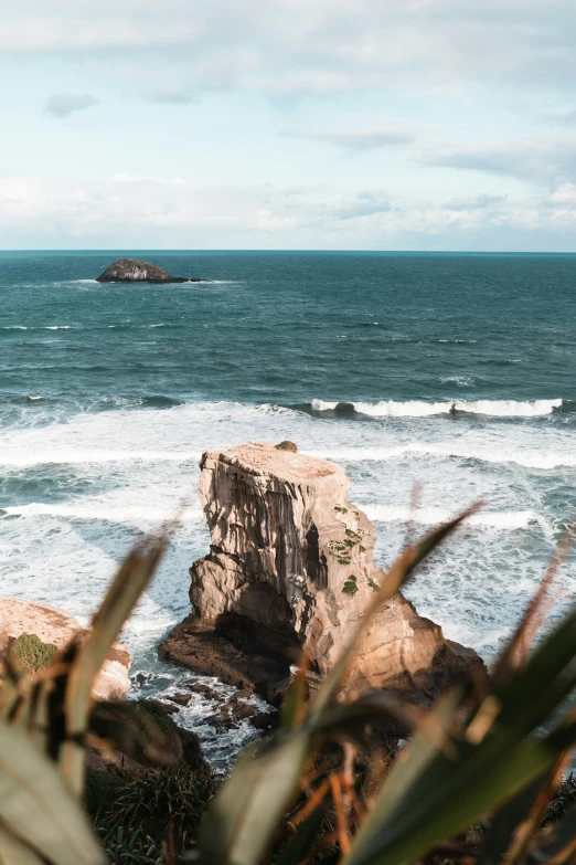 an ocean scene with waves crashing against a rock