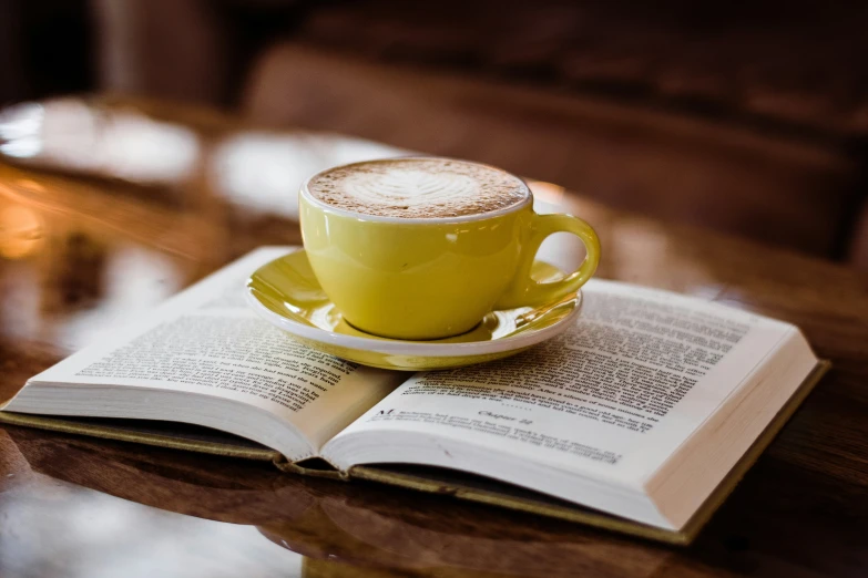 an open book with a cup of coffee sitting on it