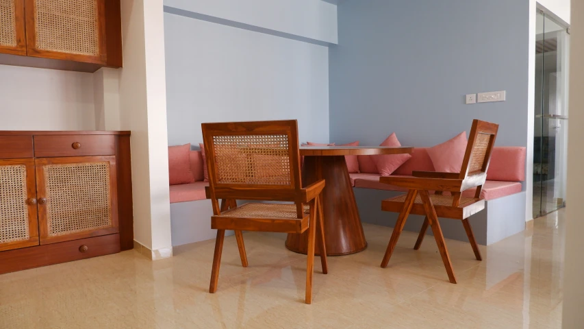 wooden furniture and pink pillows sit in a dining room