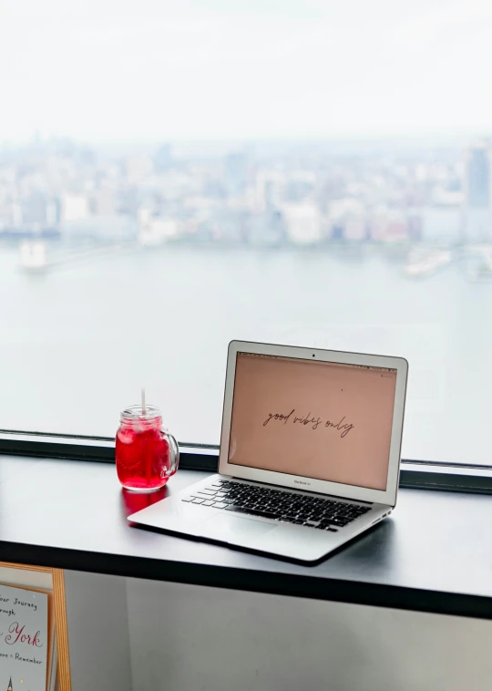 a laptop sits on a desk in front of the window