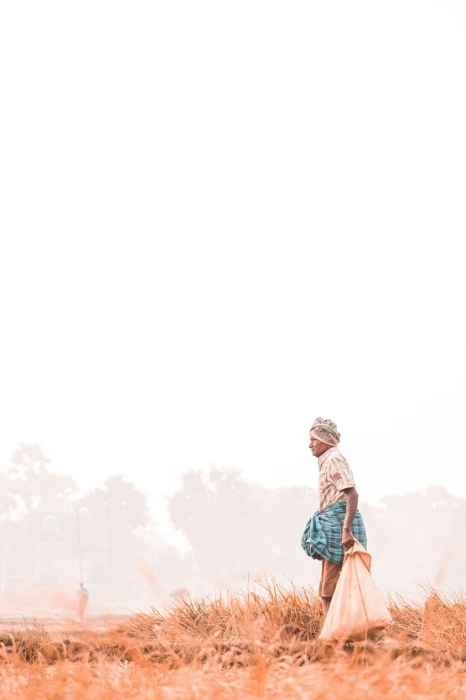 a woman in a straw hat walking through an empty field