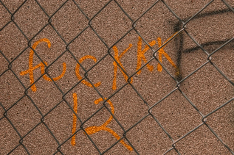 graffiti written in orange on the brown surface